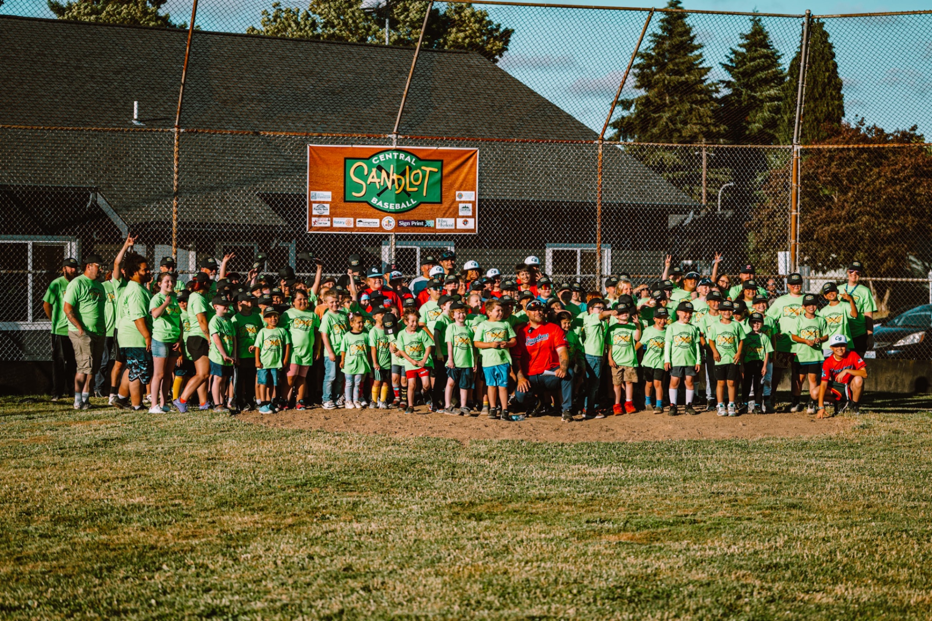 Children and adults gathered together at a community sandlot game